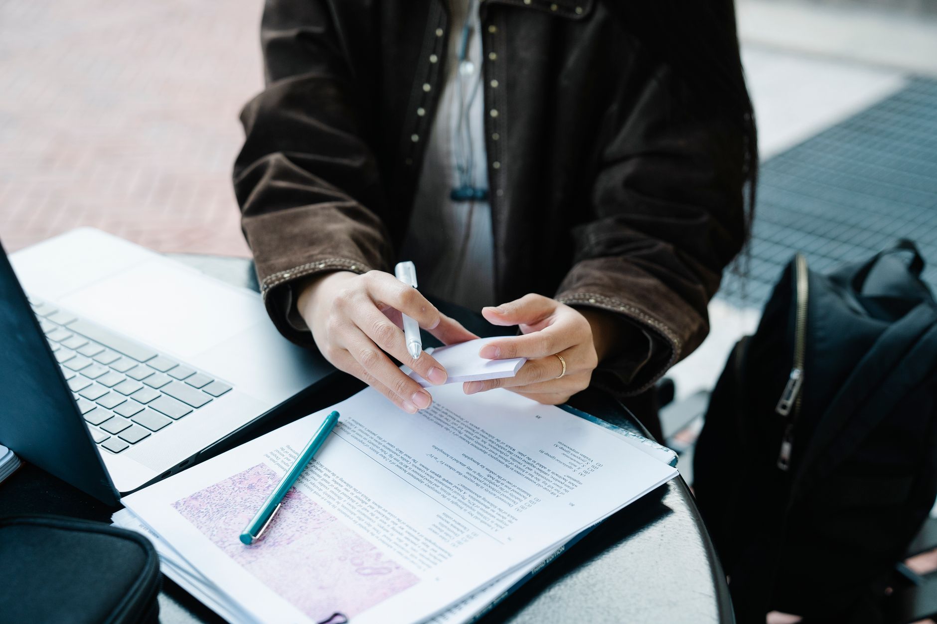 A student reading a long document on a laptop and highlighting notes with a pen.