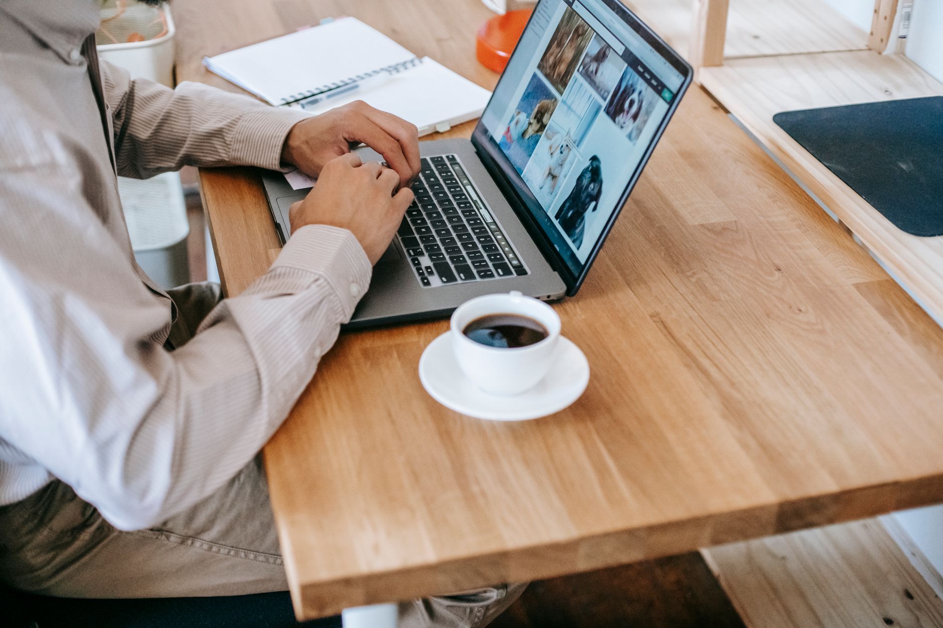 A writer comparing handwritten notes beside an open laptop on a wooden desk