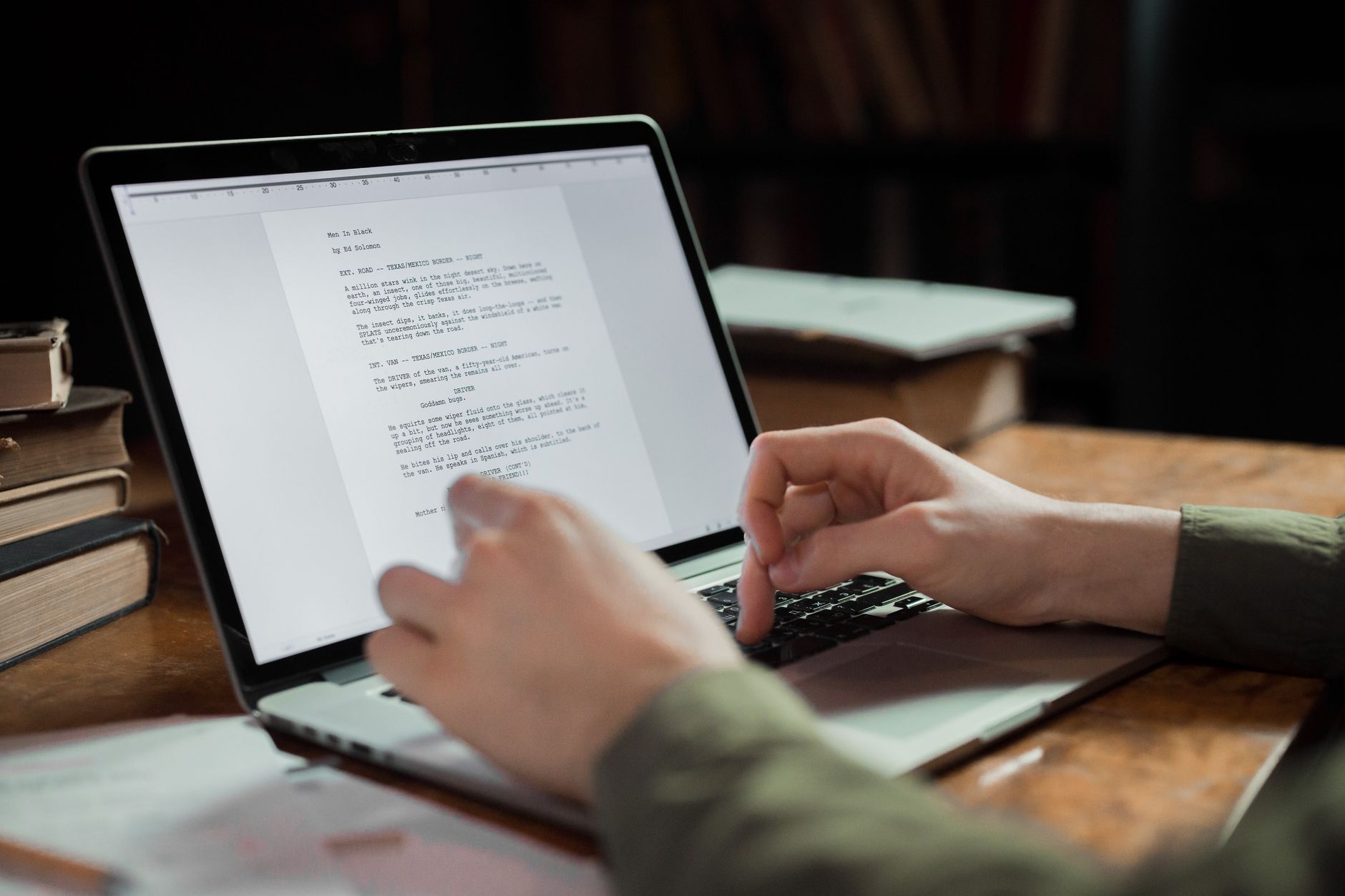 Close view of fingers resting on a laptop keyboard while text fills the screen