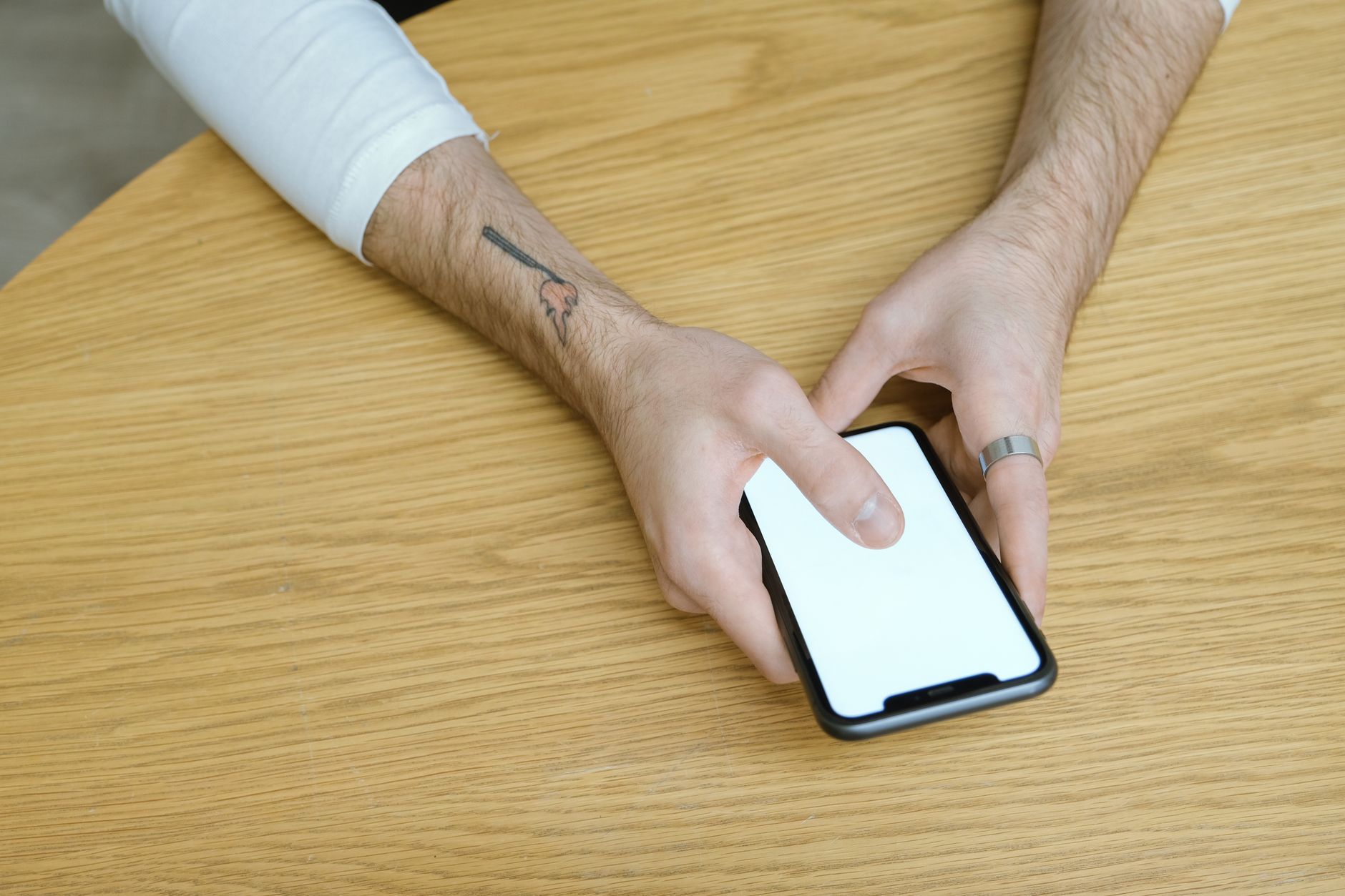 Hands holding a smartphone over a cafe table beside a cup of coffee