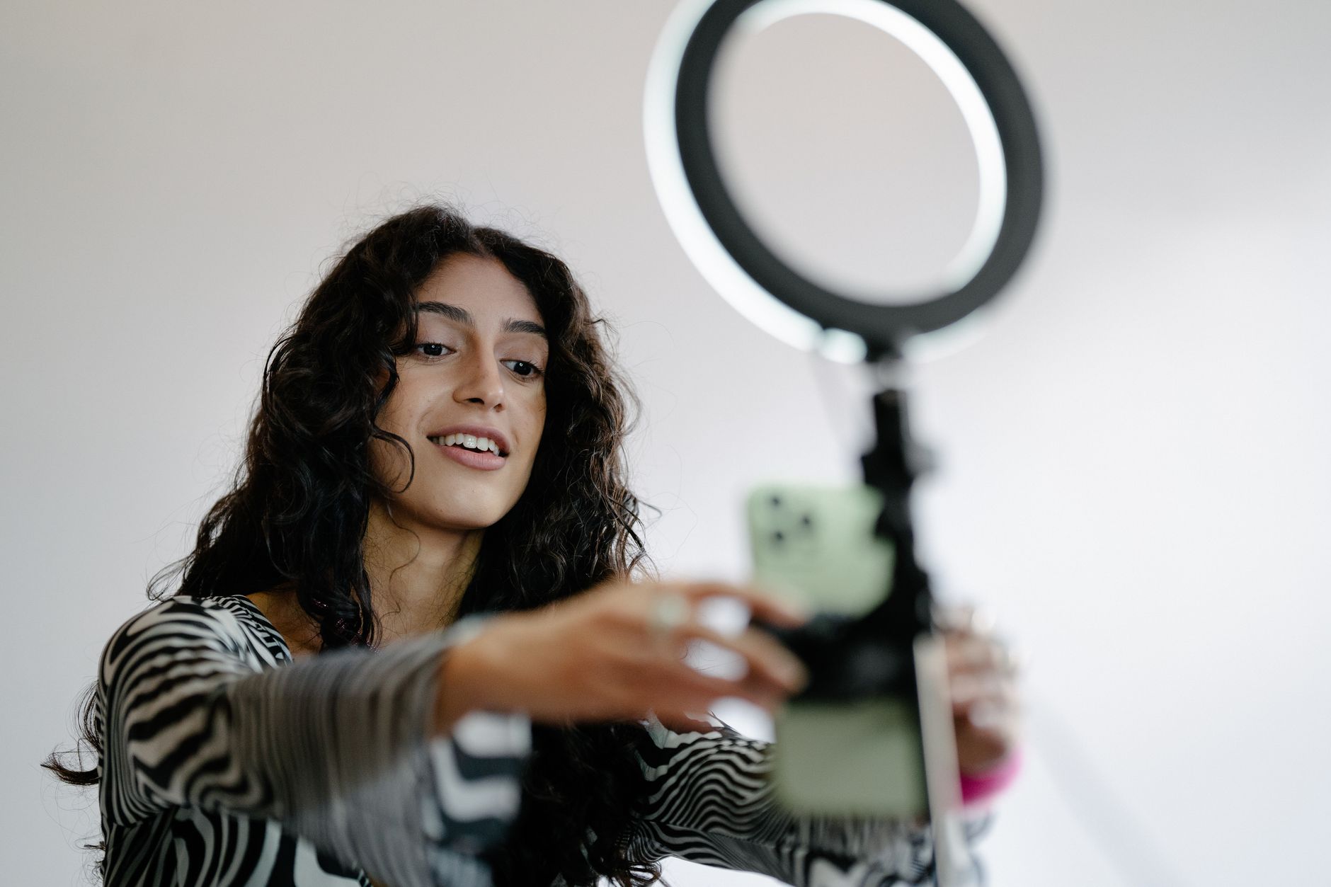 A small business owner filming a product flat lay with a ring light and a phone on a tripod.