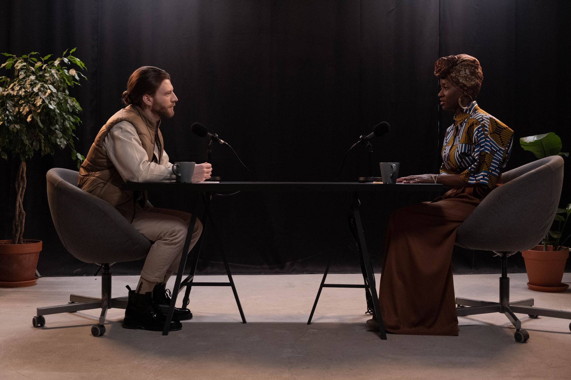 Two people speaking into professional microphones during a podcast recording